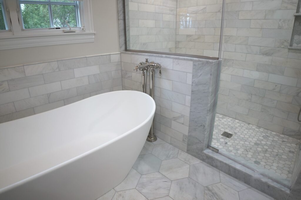 Hexagonal tiled bathroom floor laid around a freestanding bath