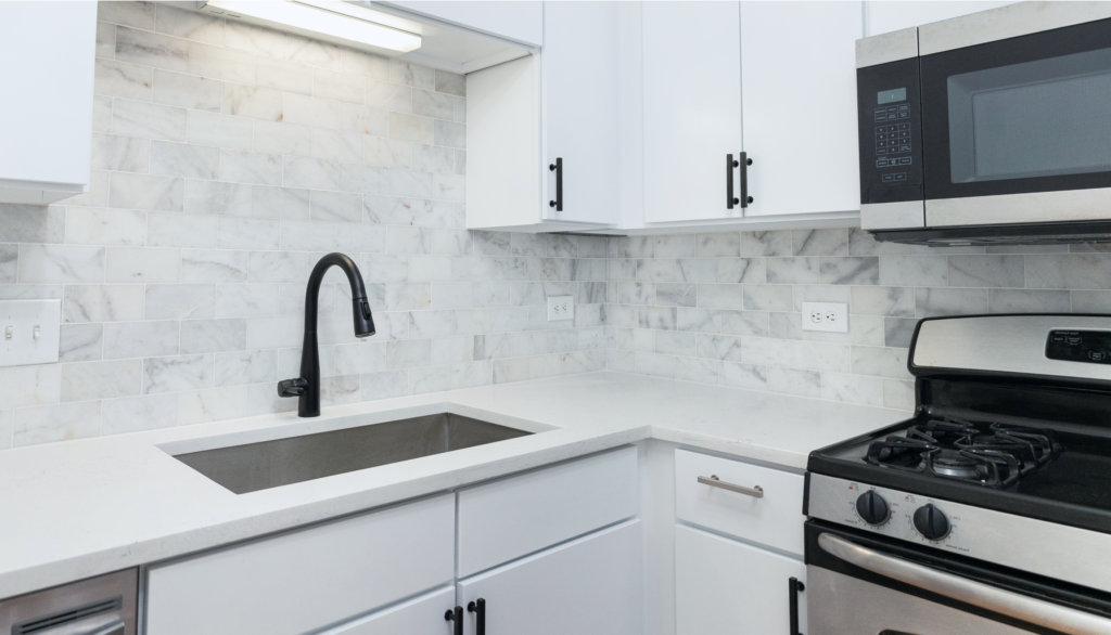 renovated kitchen counter with ceramic backsplash and white cabinets