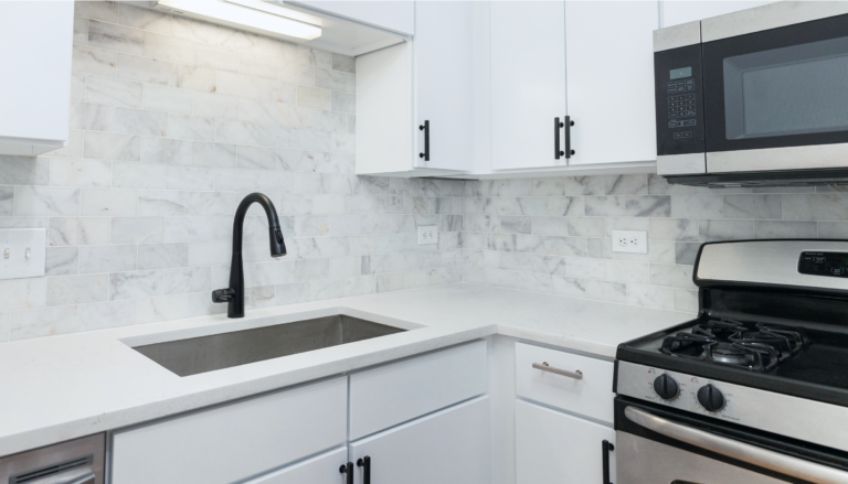 renovated kitchen counter with ceramic backsplash and white cabinets