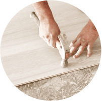 hands hammering down hardwood floor panel