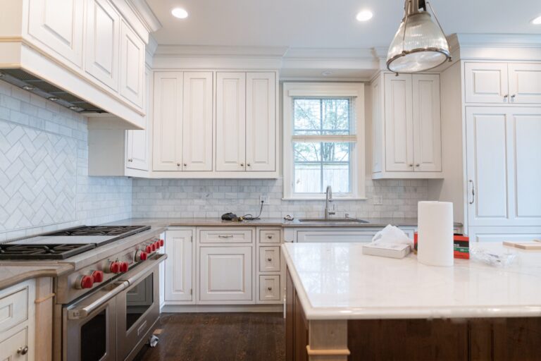 Remodelled Chicago kitchen with cream shaker cabinetry, a herringbone marble backsplash, a professional range and a marble-topped island