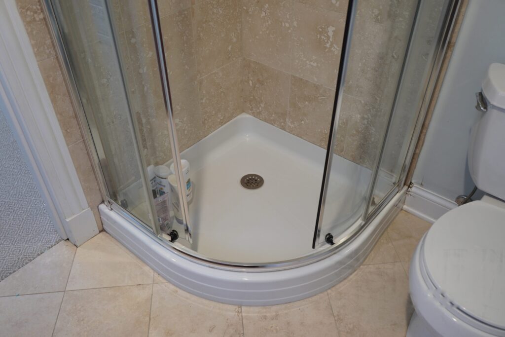 Corner shower enclosure with curved glass doors and a white shower base