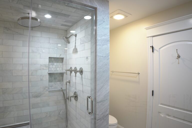 Marble subway tiled shower with a recessed niche, rainfall head and a frameless glass door
