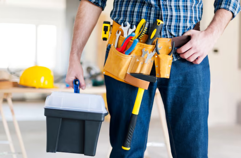 Handyman holding toolbox and wearing tool belt