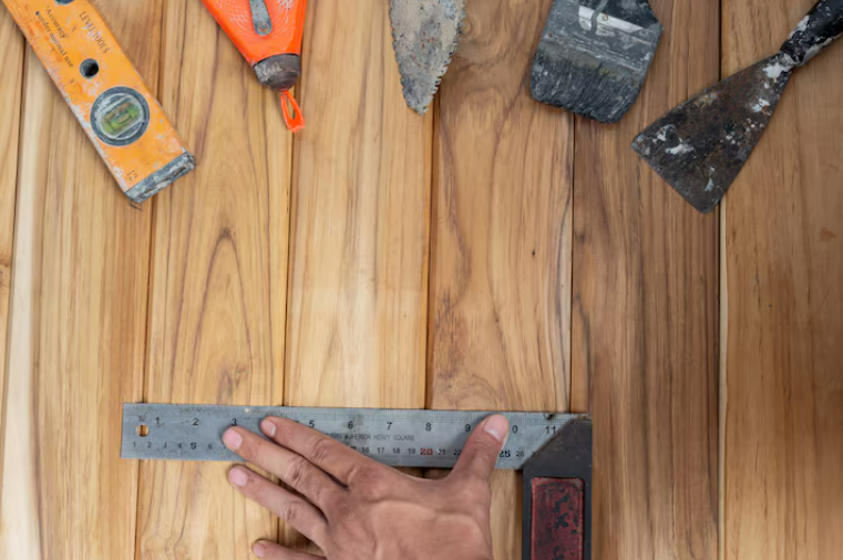 Hand measuring wood with a square and various carpentry tools