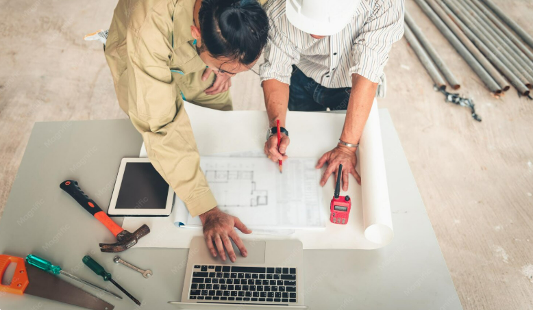 Two construction workers reviewing blueprints on a table