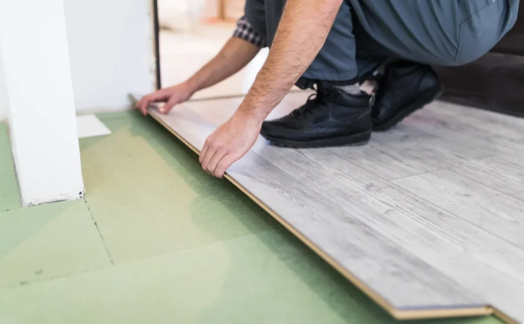 Installer laying luxury vinyl plank flooring over underlayment