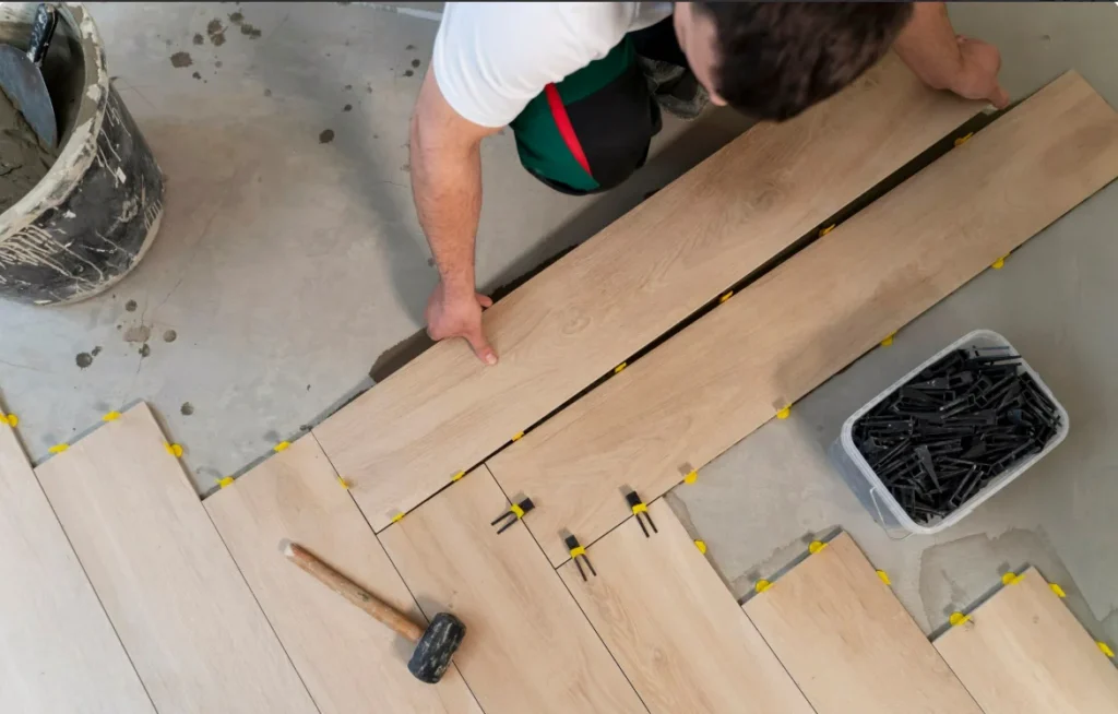 Installer laying hardwood flooring planks with leveling spacers