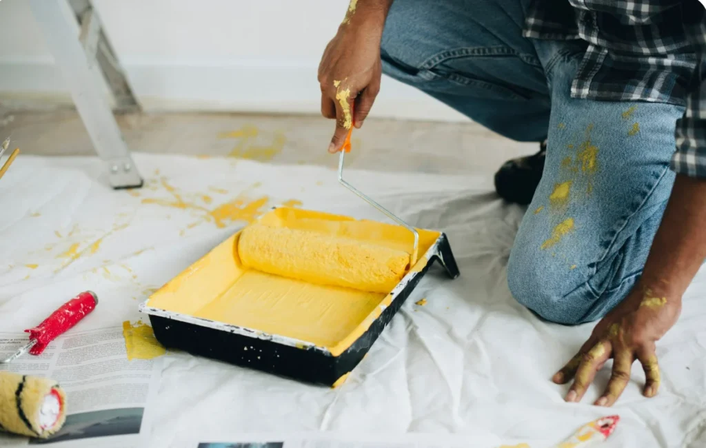 Painter preparing roller with yellow interior wall paint